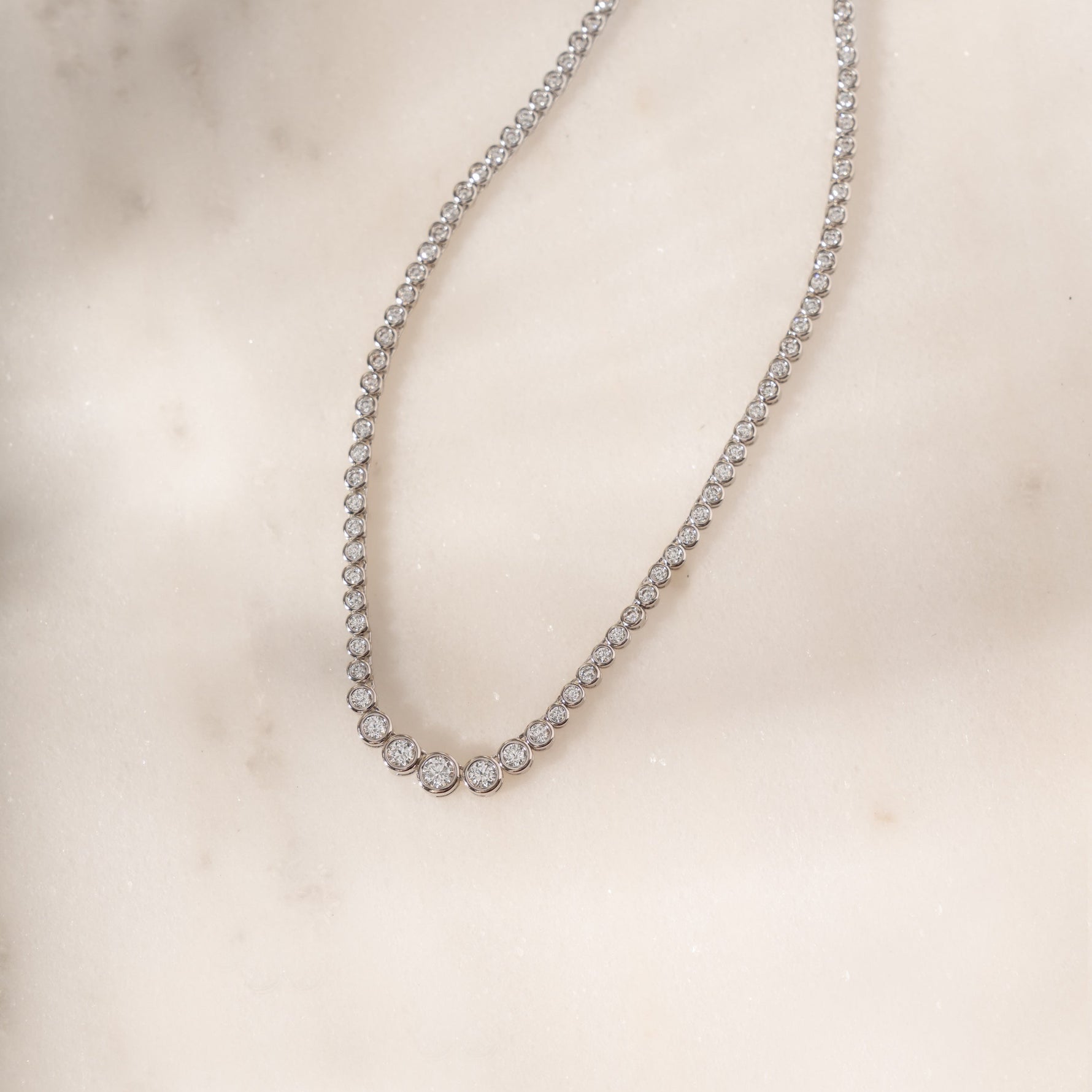 flat lay of a silver tennis choker featuring a gradient diamond design.