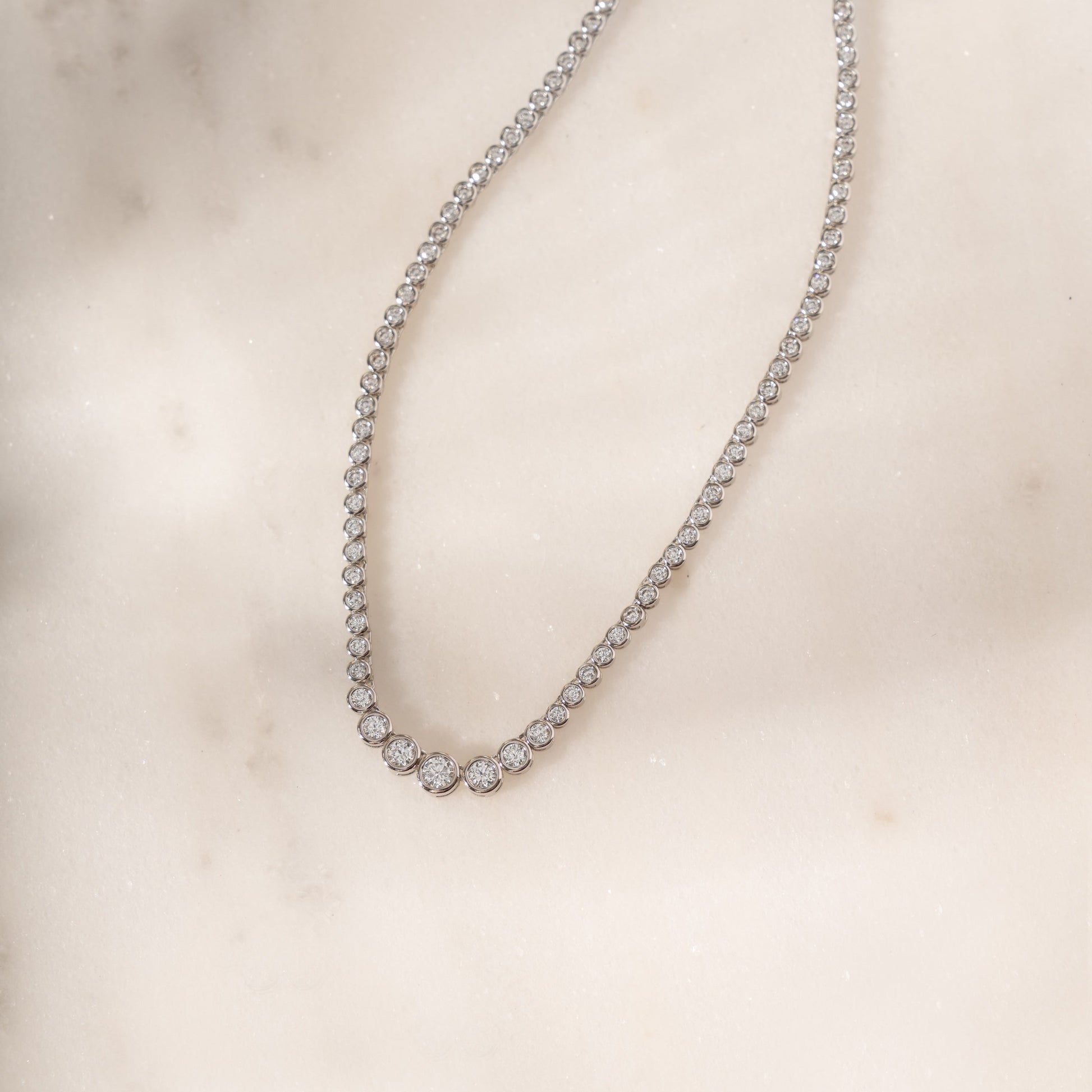 flat lay of a silver tennis choker featuring a gradient diamond design.