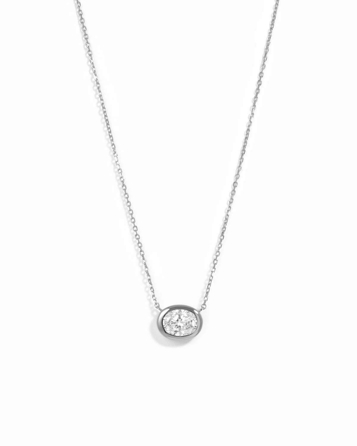 Silver east-west oval CZ bezel pendant necklace on a white background.