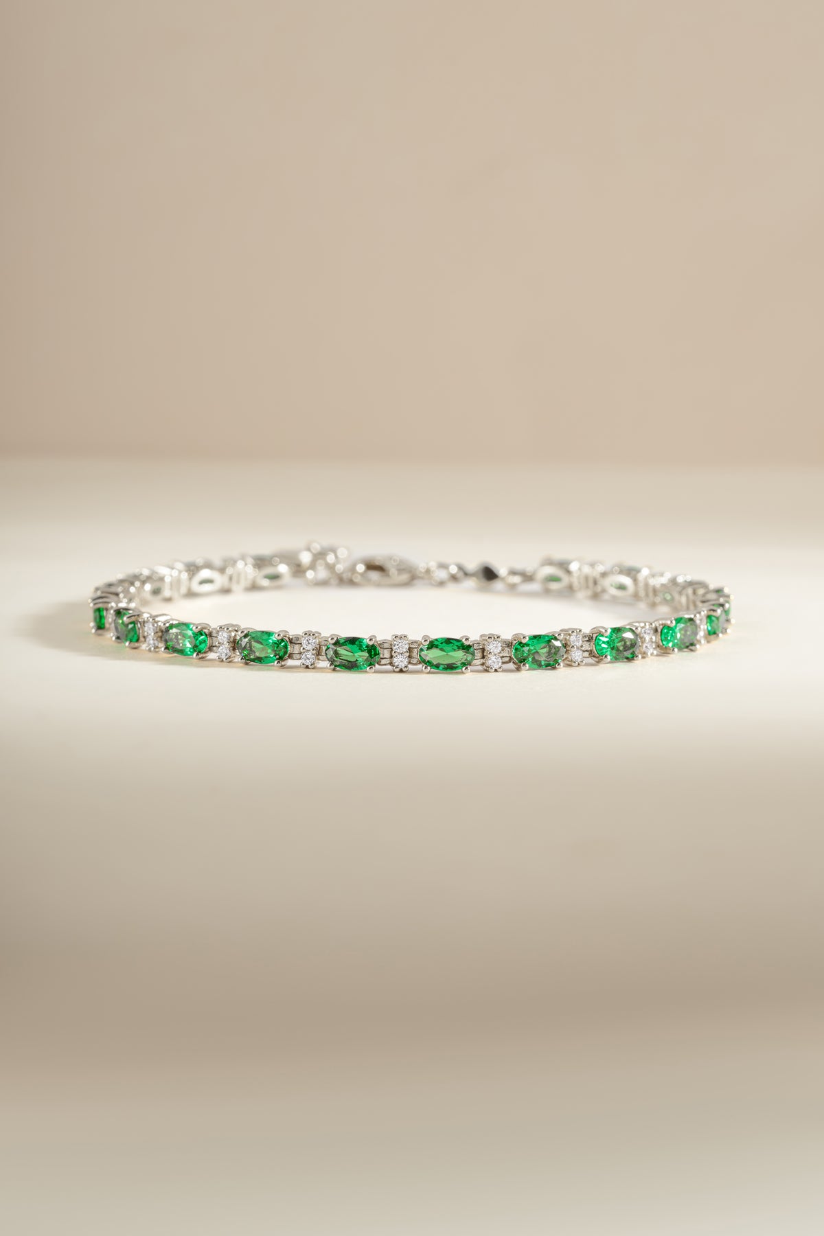 Silver tennis bracelet with oval green and round white cubic zirconia stones. 