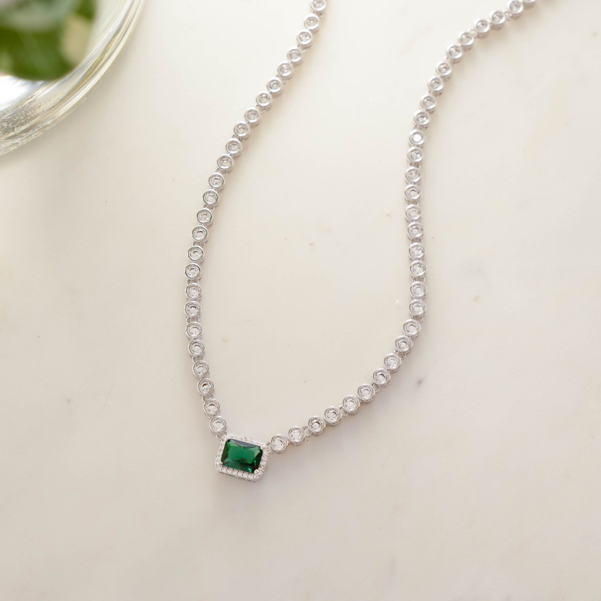 Sterling silver diamond tennis emerald necklace on white background 