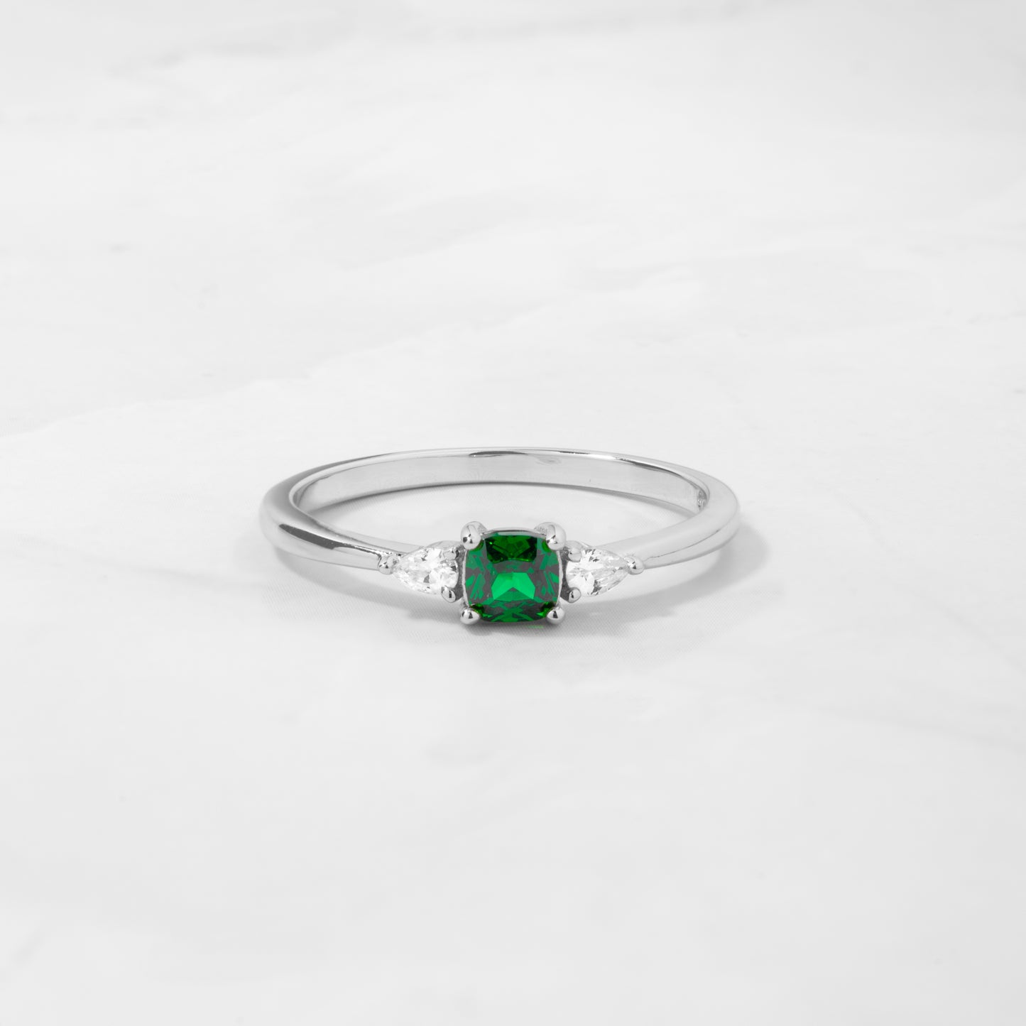 a sterling silver emerald ring with cushion center and pear side stones