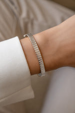 Silver fluted bangle worn alone on a model's wrist with a white shirt.