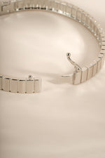 Open silver fluted bangle showing its box clasp and safety latch.