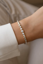 Silver graduated bezel tennis bracelet worn alone on a model's wrist.