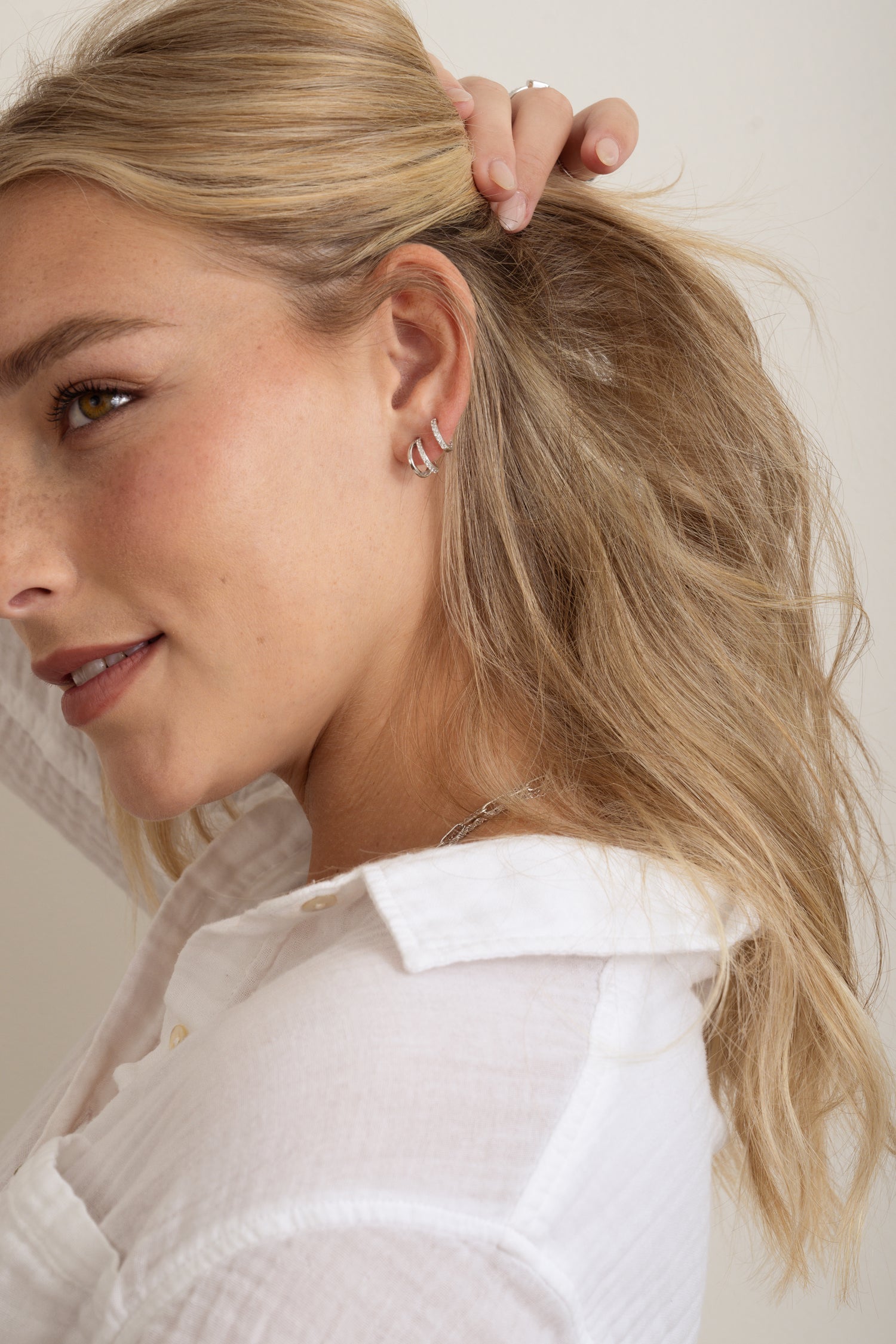 model wearing small silver hoops and huggie earrings