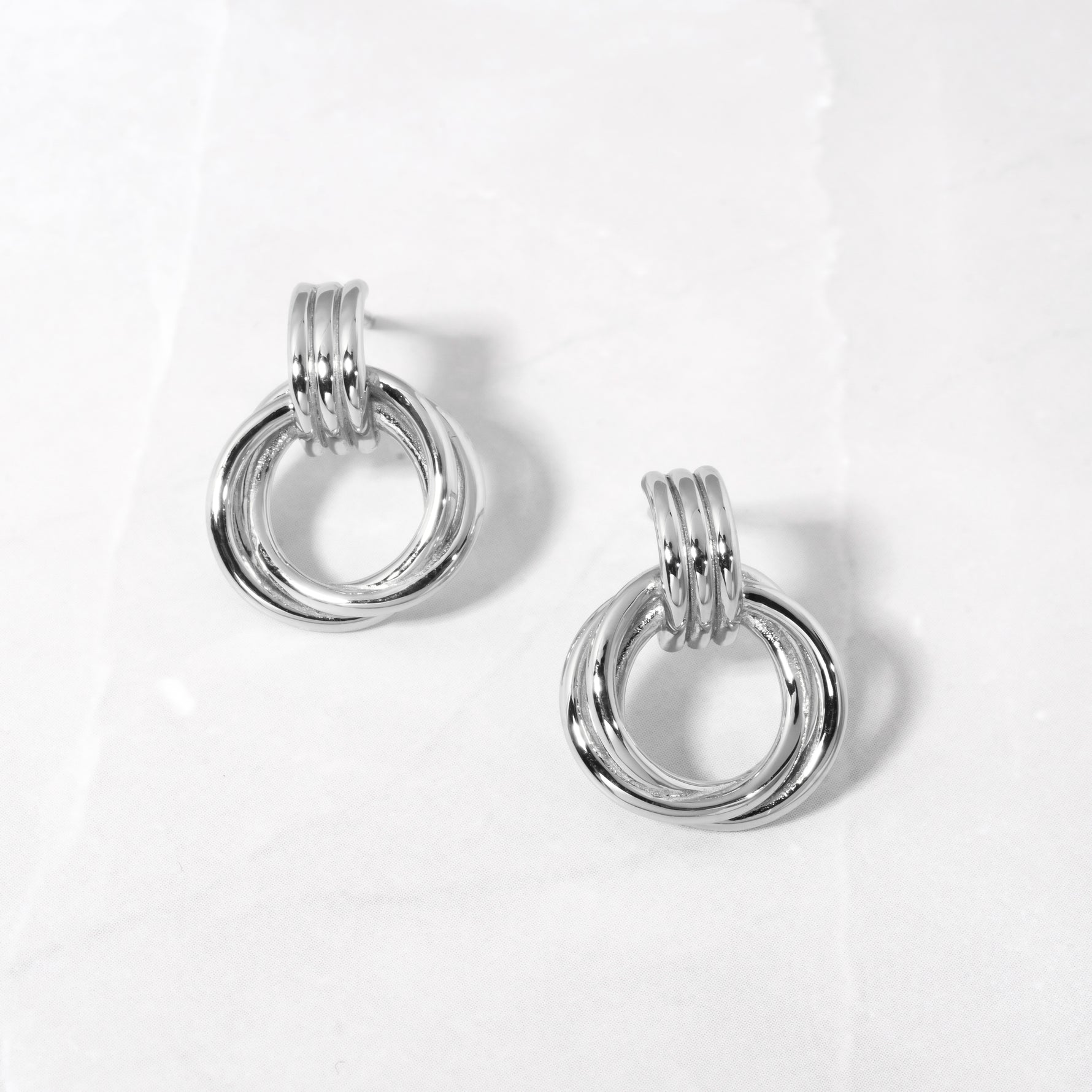 flat lay of sterling silver hoop earrings, highlighting the fluid, curved knot detail.