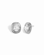 Silver oval bezel statement stud earrings with clear cubic zirconia, shown from the front and side on white.