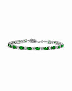 Silver tennis bracelet with alternating oval emerald and round white stones.