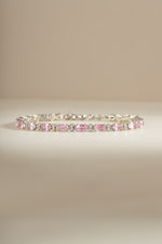 A silver tennis bracelet featuring a row of alternating pink oval gemstones and white round diamonds.
