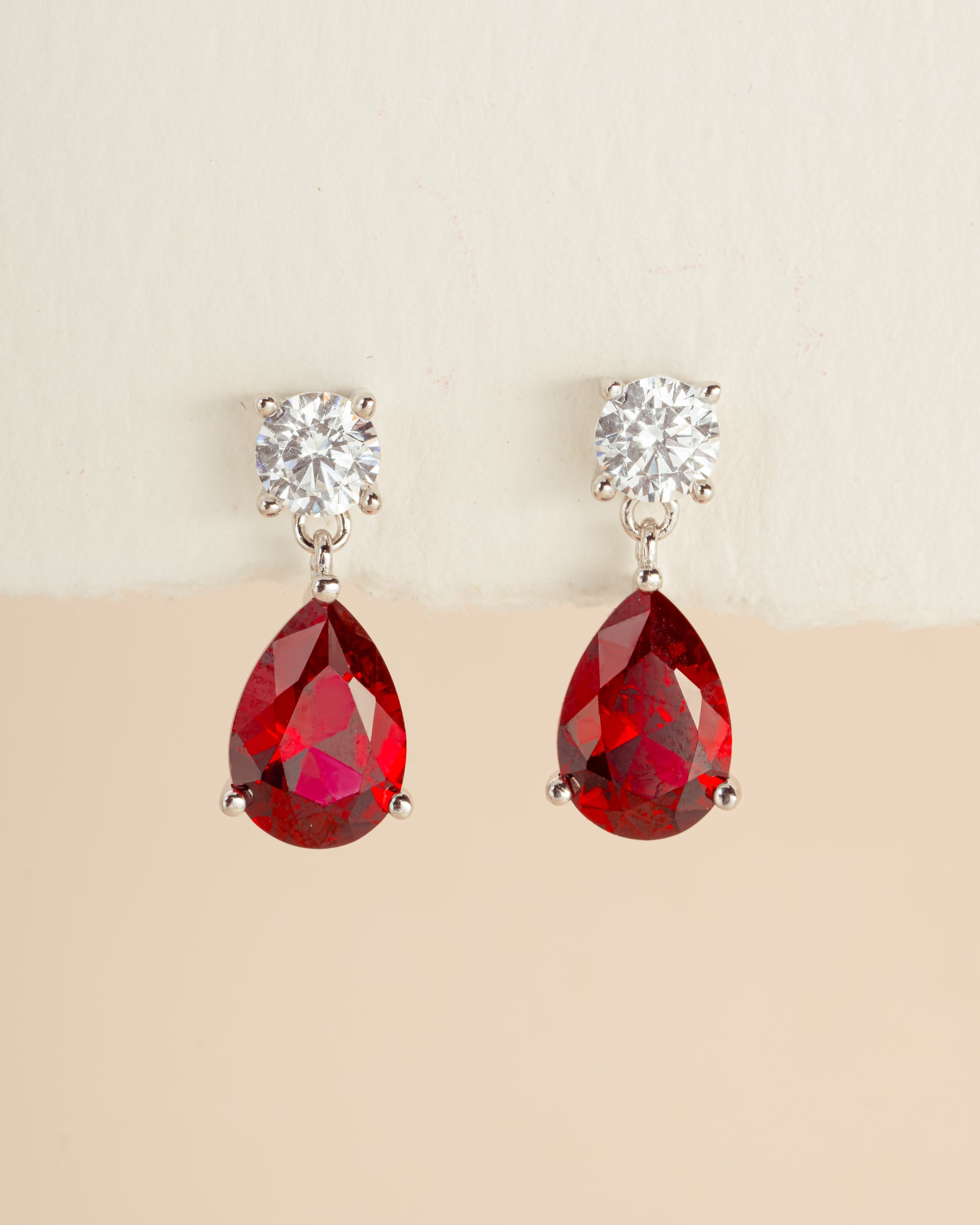 Silver Camille Ruby Pear Drop Earrings by Sami Jewels displayed on a model featuring dangling ruby and silver earrings.