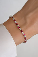 Silver Ruby Tennis Bracelet by Sami Jewels shown on woman's wrist with sparkling red rubies and elegant silver setting.