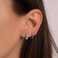 Model wearing silver aquamarine huggie earrings in her first piercing, a small silver hoop earring in her second piercing, and a silver tiny diamond stud in her third piercing