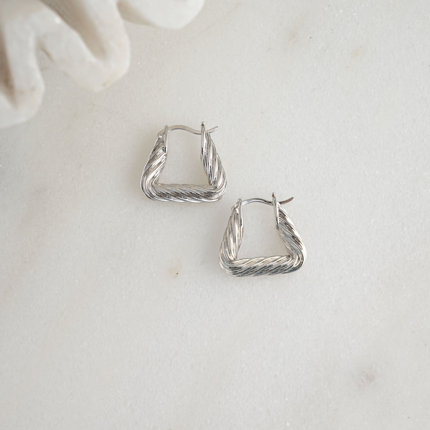 Chunky silver earrings with a bold triangle shape.