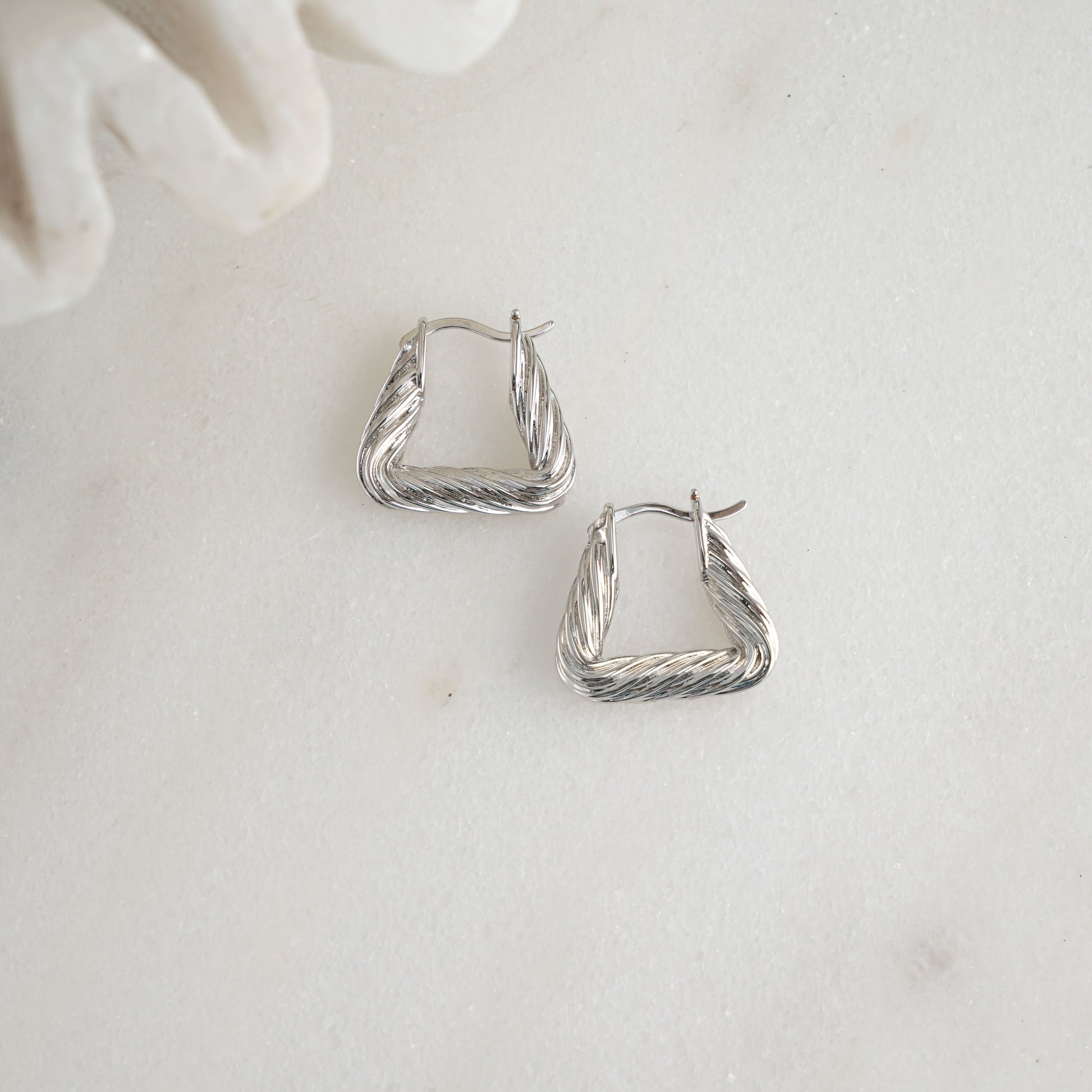 Chunky silver earrings with a bold triangle shape.