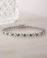 closeup image of silver tennis bracelet with emerald green cubic zircona stones