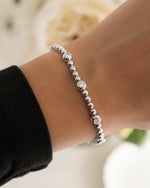 model wearing silver beaded bracelet with big cz stones