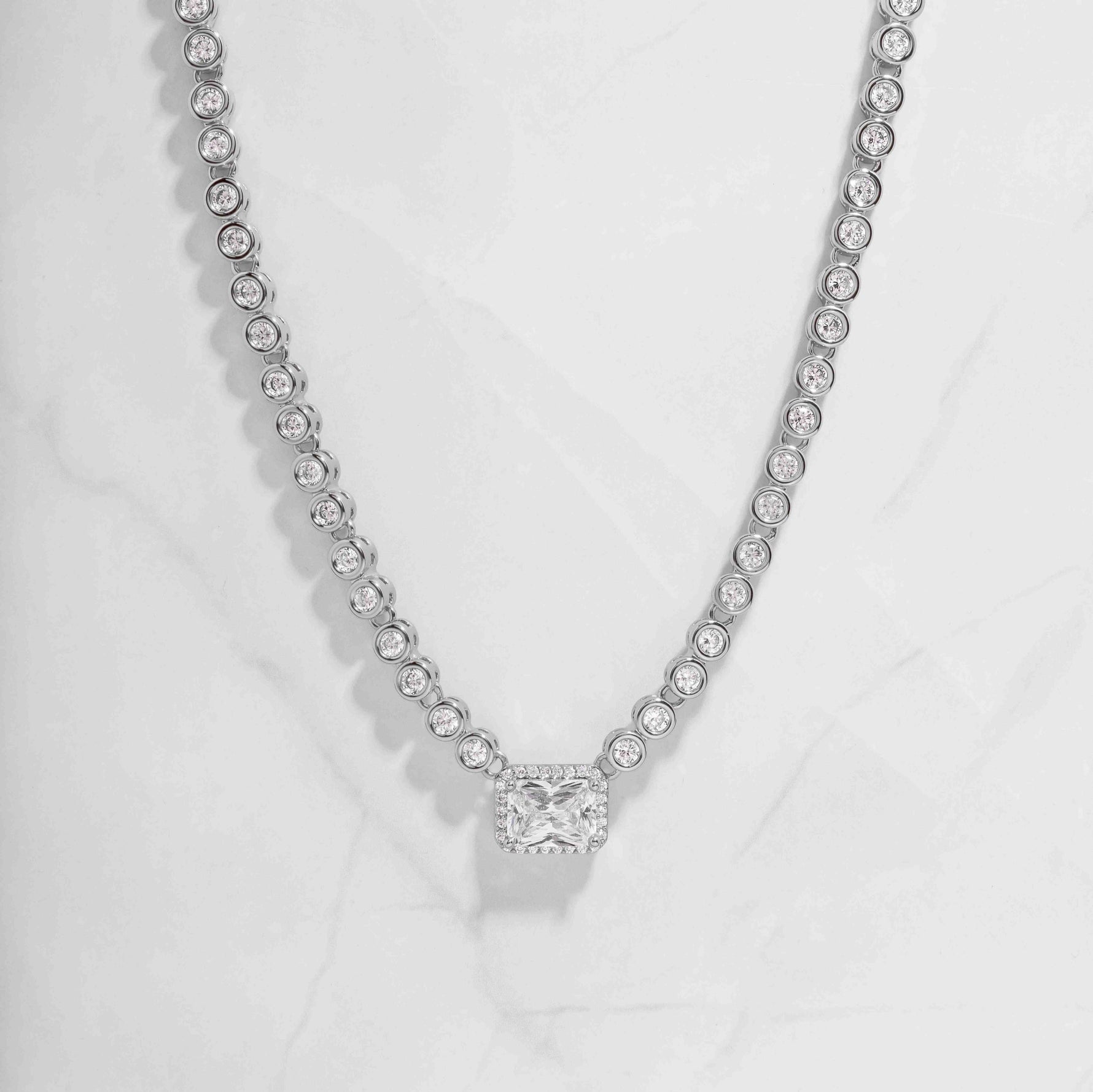 Sterling silver tennis necklace for her with tiny diamonds and baguette pendant, on white marble background