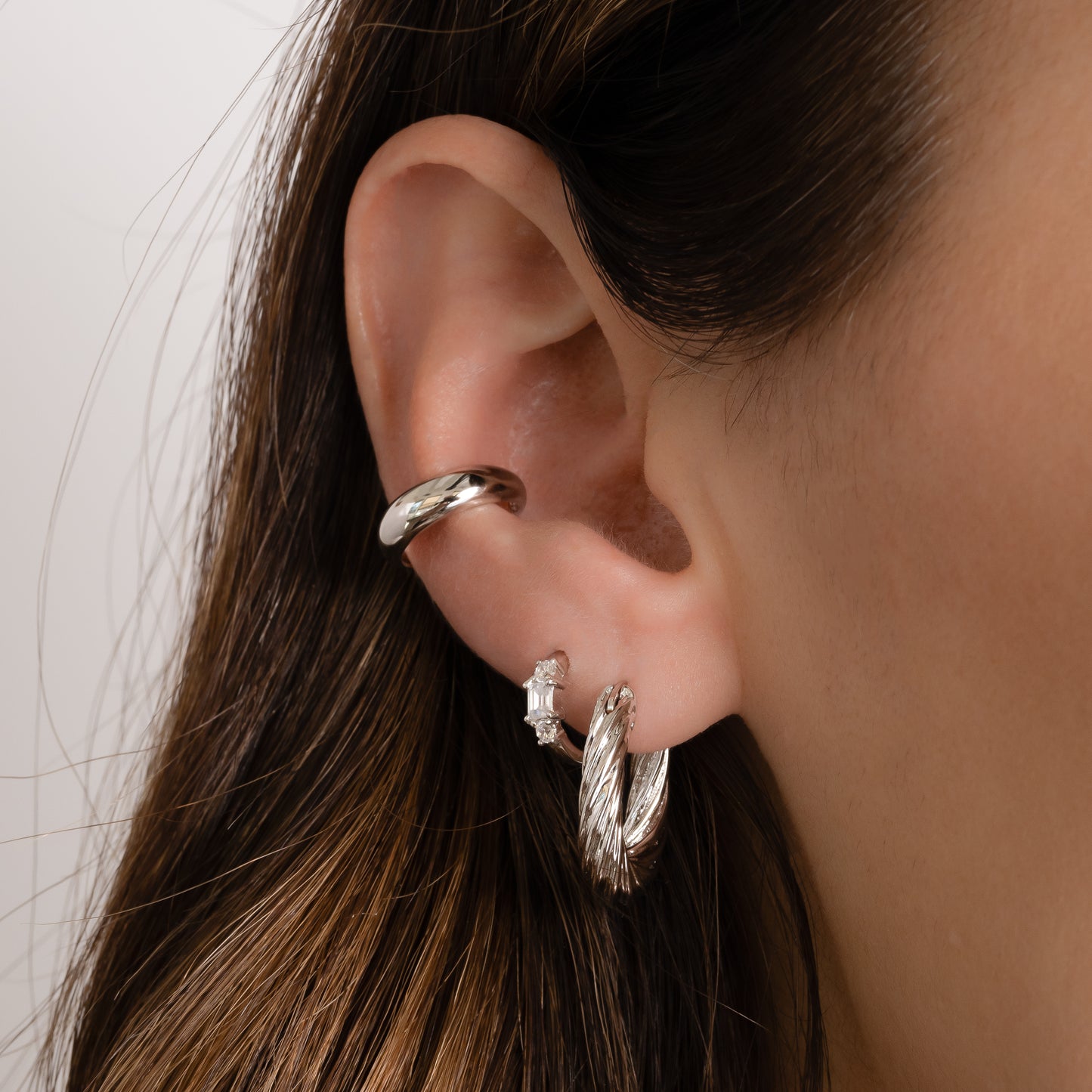 silver ear cuff stacked with a chunky silver hoop