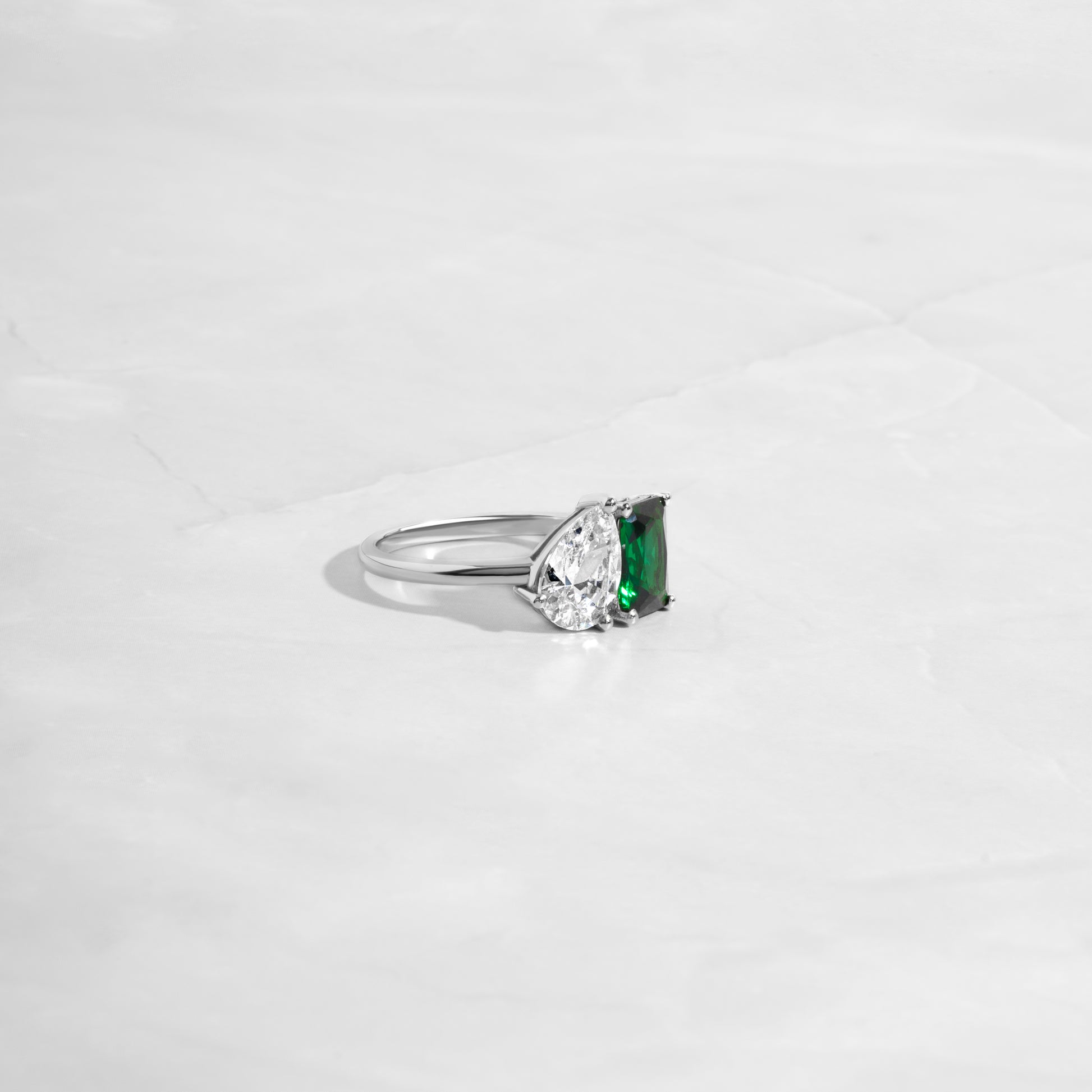 Side profile of Toi et Moi Ring with an emerald cut and pear-shaped diamond, set in sterling silver, as a unique engagement ring or statement ring.