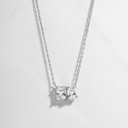 Close-up of a silver Toi et Moi bridal necklace featuring emerald cut and pear shape cubic zirconia. 