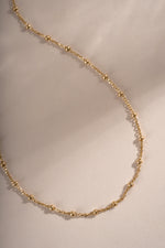 Close-up of a gold beaded necklace by Sami Jewels, showcasing its simple and elegant design.
