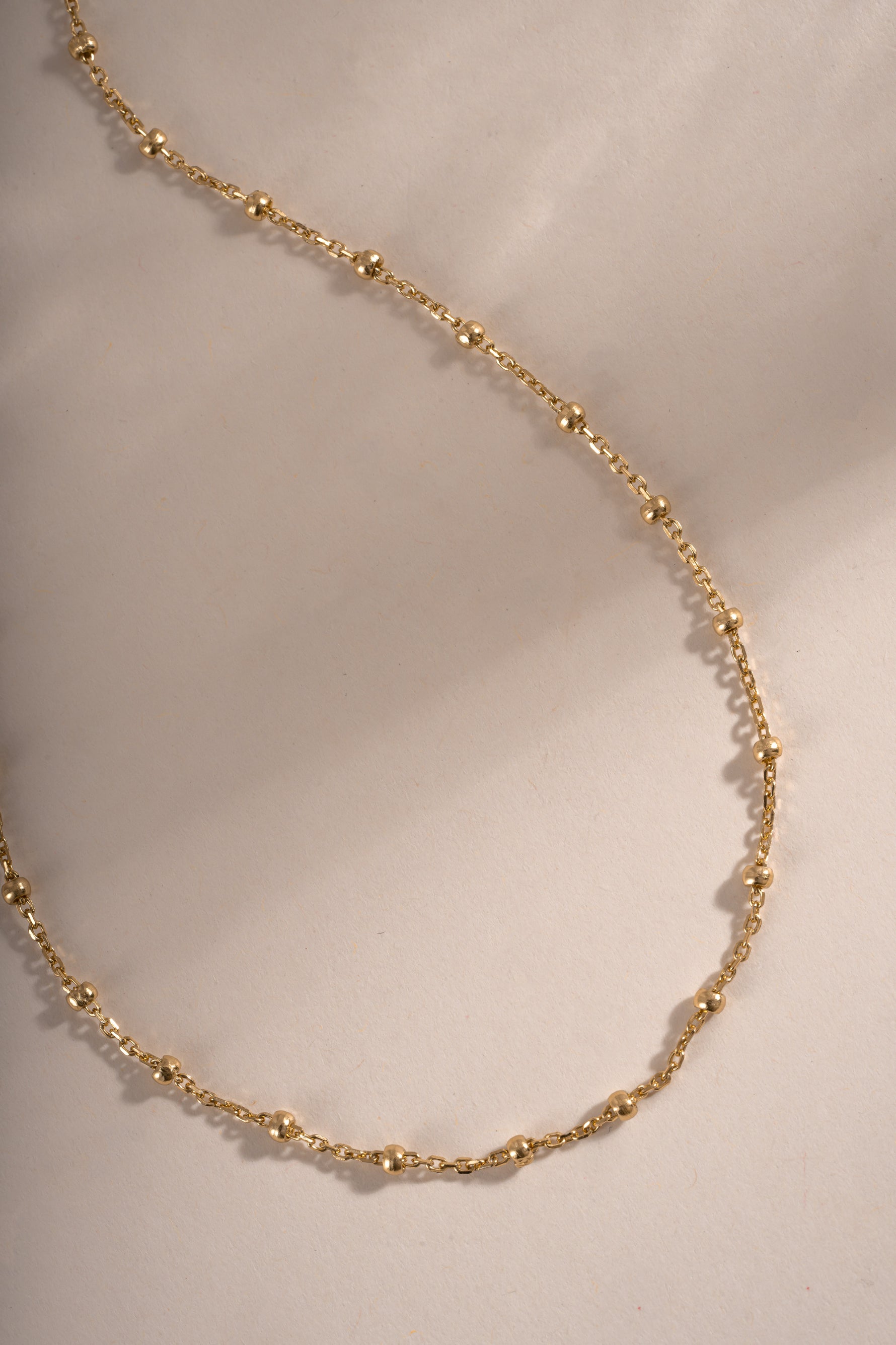 Close-up of a gold beaded necklace by Sami Jewels, showcasing its simple and elegant design.
