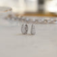 Sterling silver bridal hoop earrings with tiny pave diamonds on marble background