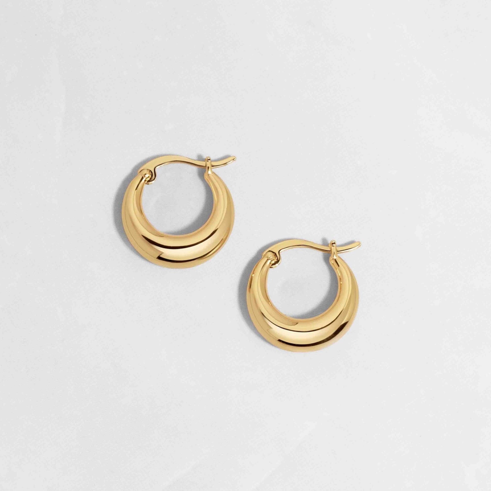 Gold statement hoop earrings on white background with hinge closure