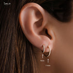 Close-up of model wearing gold pavé diamond huggie earrings, showcasing both the 8mm and 11mm sizes.