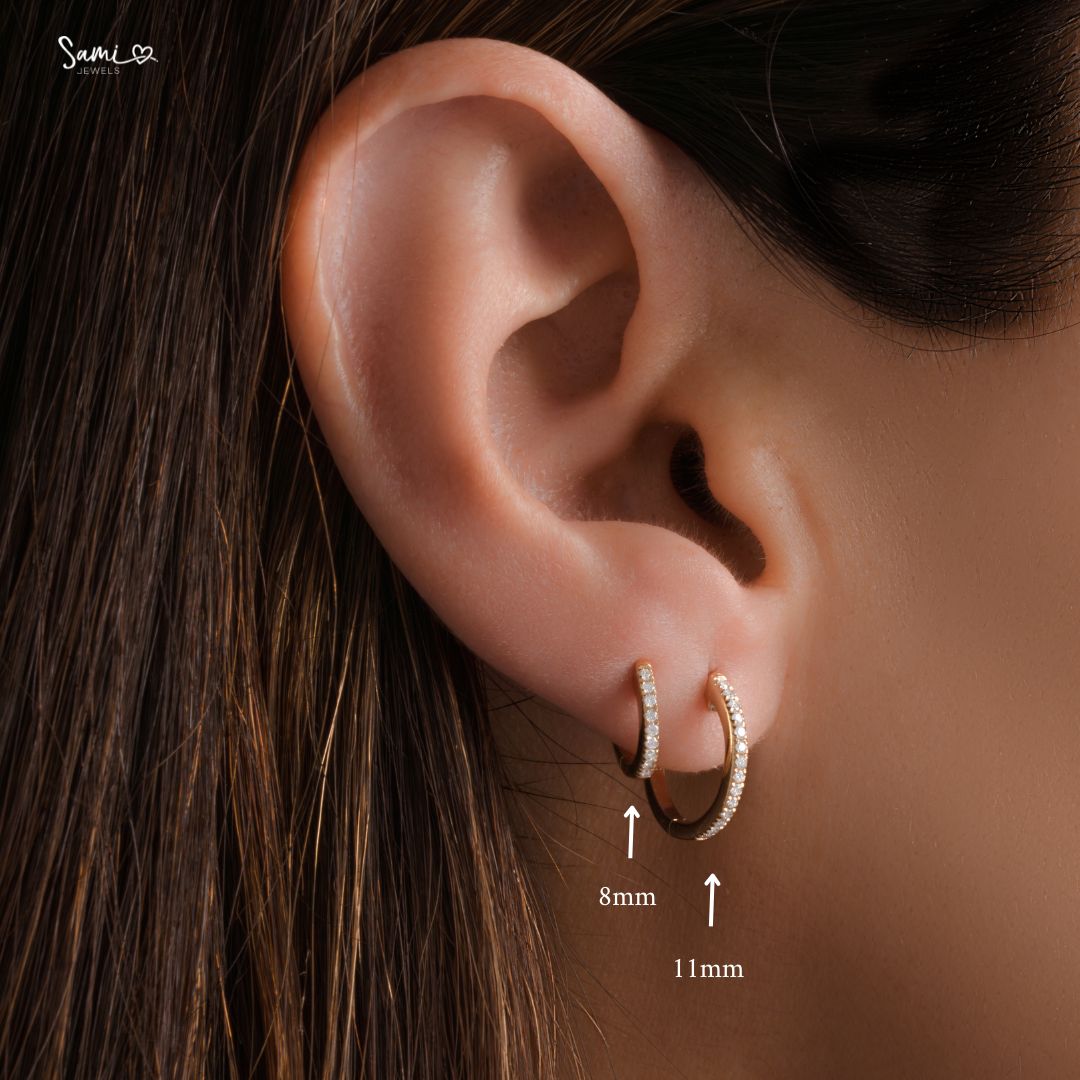 Close-up of model wearing gold pavé diamond huggie earrings, showcasing both the 8mm and 11mm sizes.