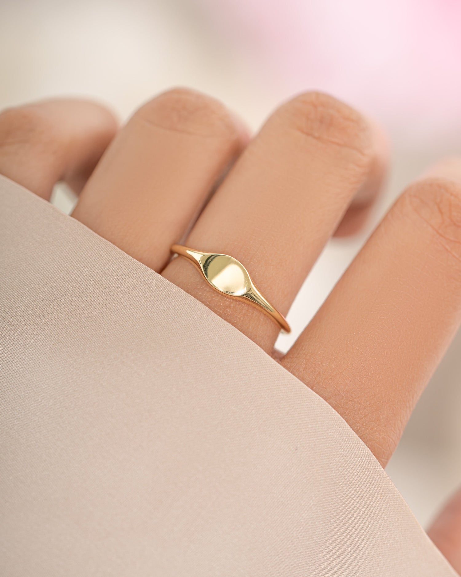 Gold small signet ring from Sami Jewels featuring a sleek, minimalist design on a model's finger.