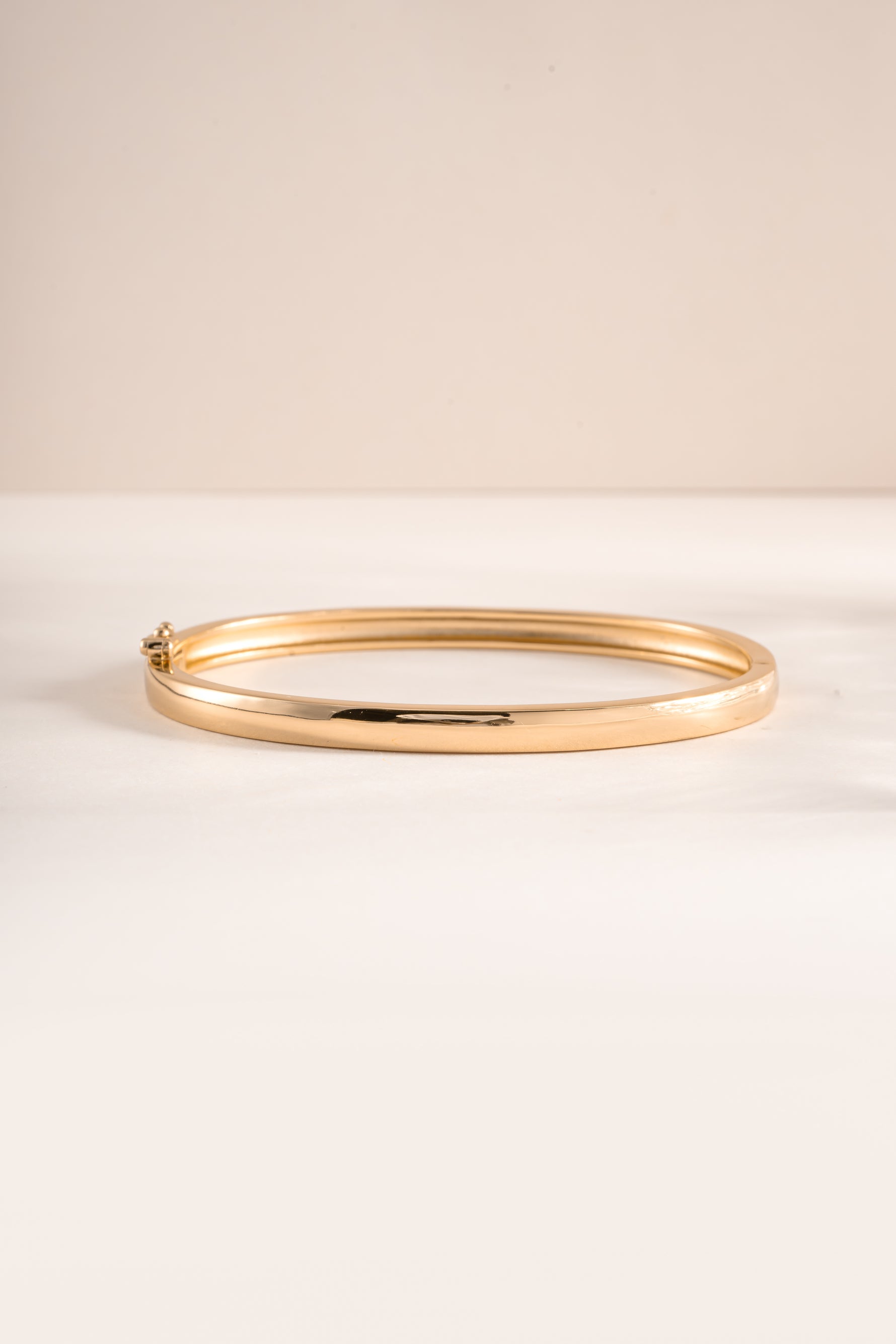Gold Sami Jewels solid bangle bracelet with smooth, polished finish, shown from a front view.