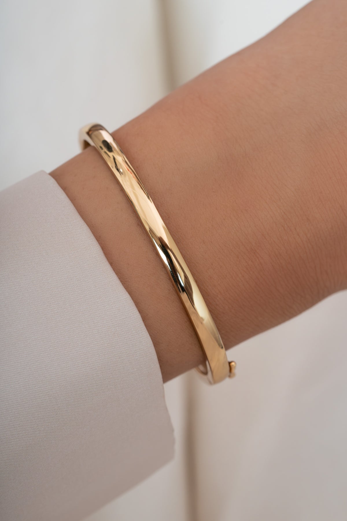 Gold solid bangle bracelet by Sami Jewels, showcasing a sleek, polished design on a model wrist.