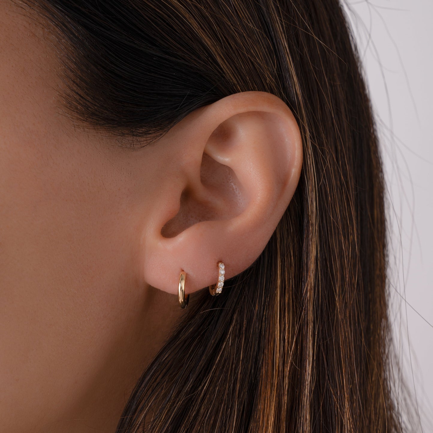model wearing gold mini huggie hoop paired with gold cubic zirconia hoop