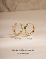 Gold diamond spiral huggie earrings by Sami Jewels featuring emerald and white cubic zirconia accents.