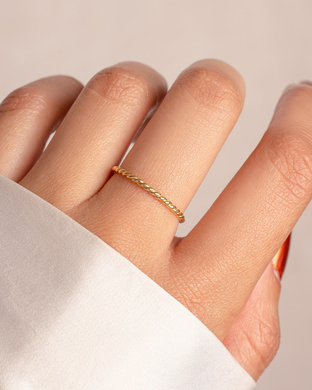 Gold spiral stacking ring from Sami Jewels, featuring a sleek, modern design displayed on a model's finger.