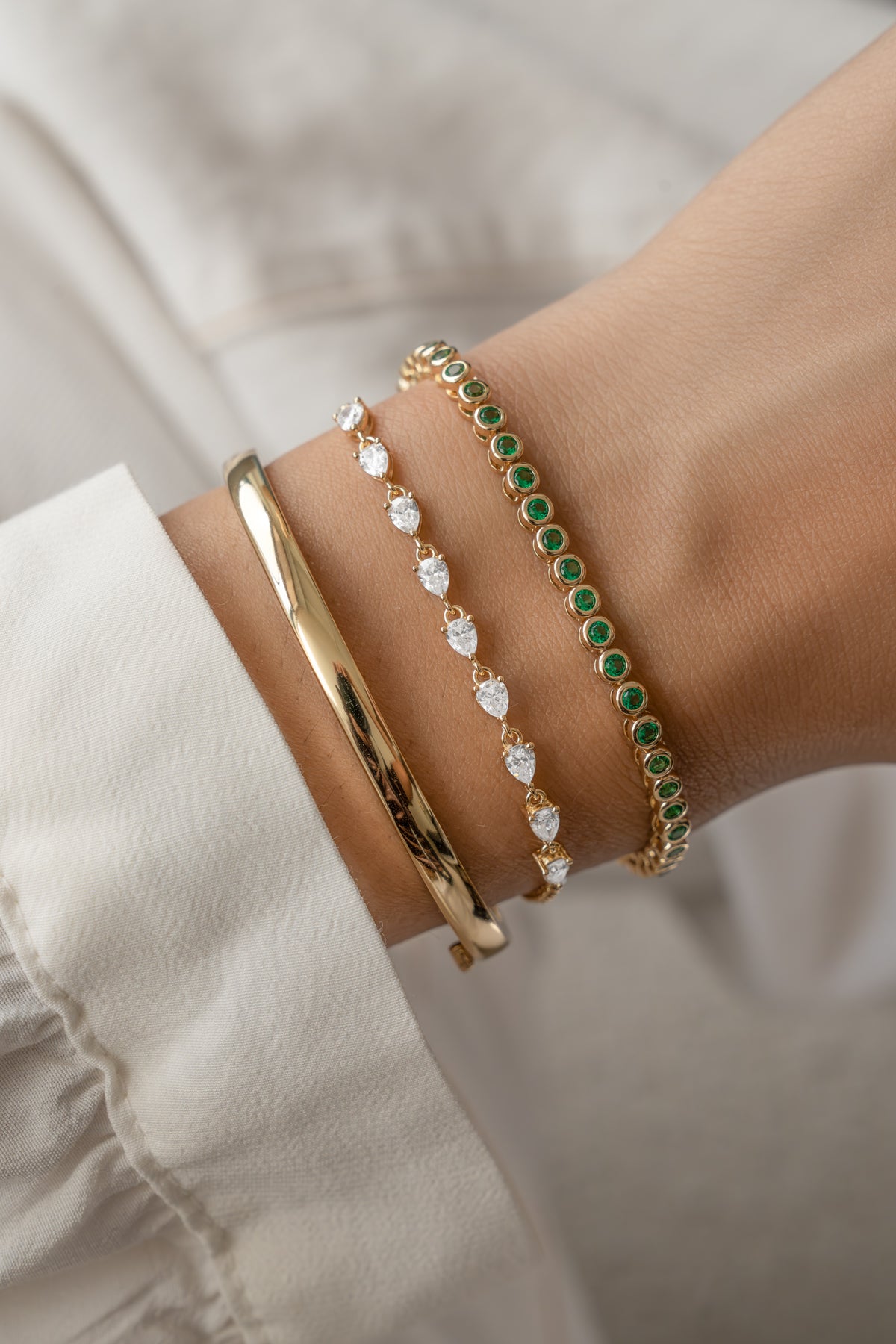 Stack of emerald bezel tennis bracelets on wrist