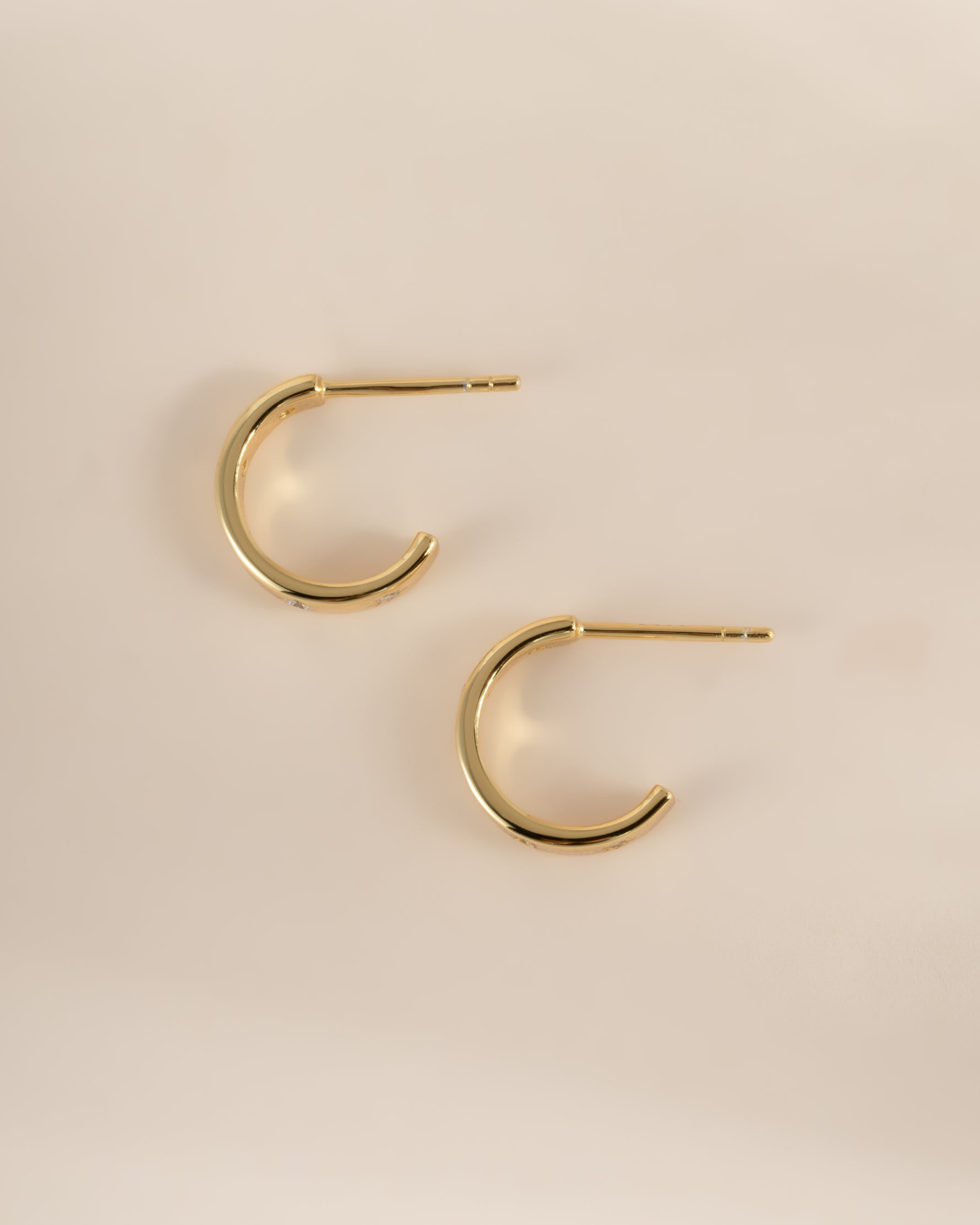 Gold hoop earrings by Sami Jewels featuring star-shaped studs, shown in a side profile view.