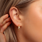 closeup of model showcasing dainty hoop earrings with celestial pattern.
