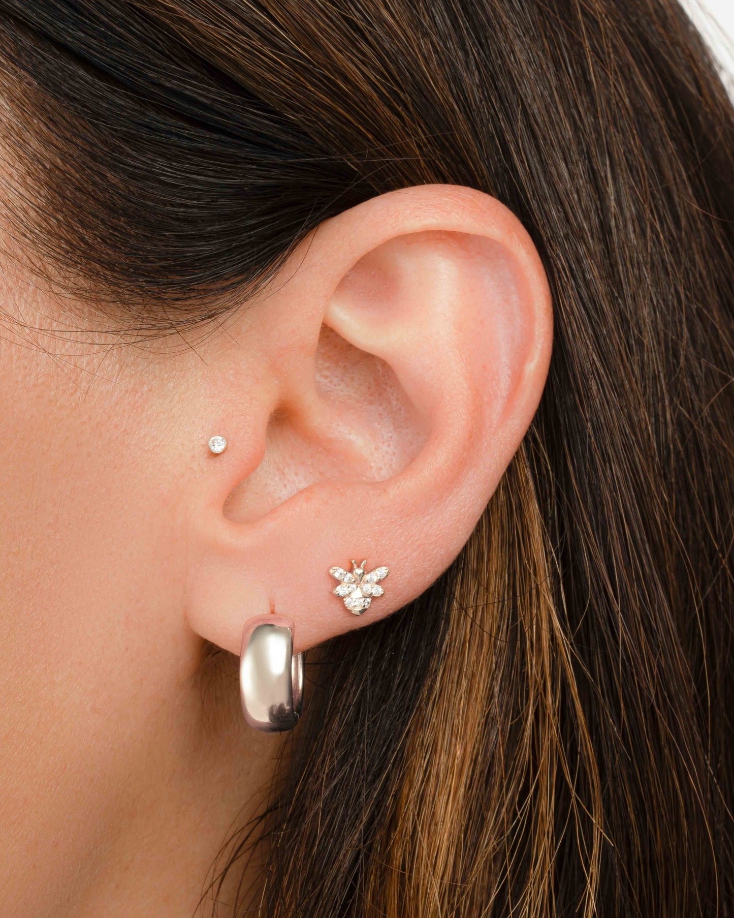 model wearing silver hoop earrings and dainty vintage earrings featuring a bee earring design