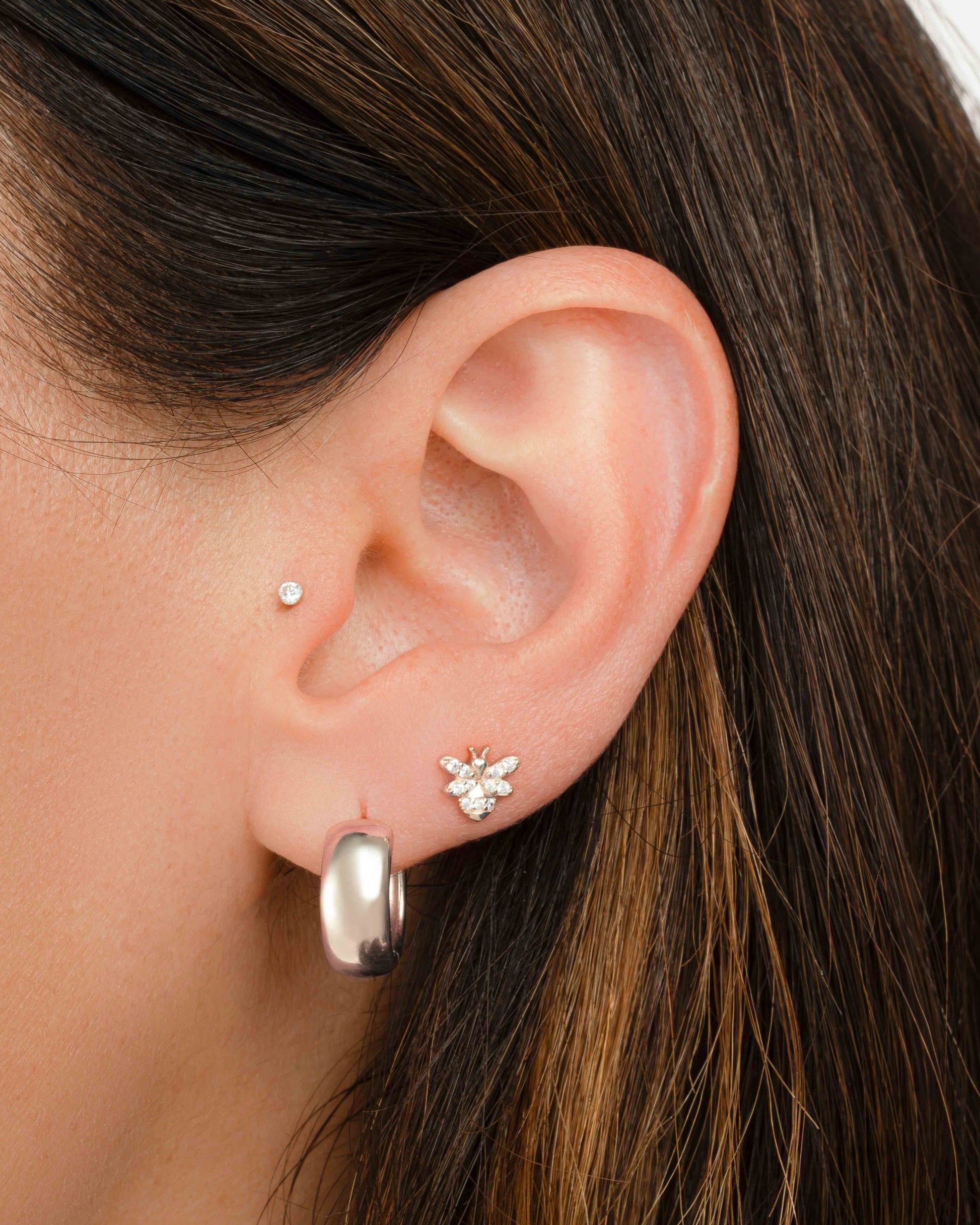 model wearing silver hoop earrings and dainty vintage earrings featuring a bee earring design