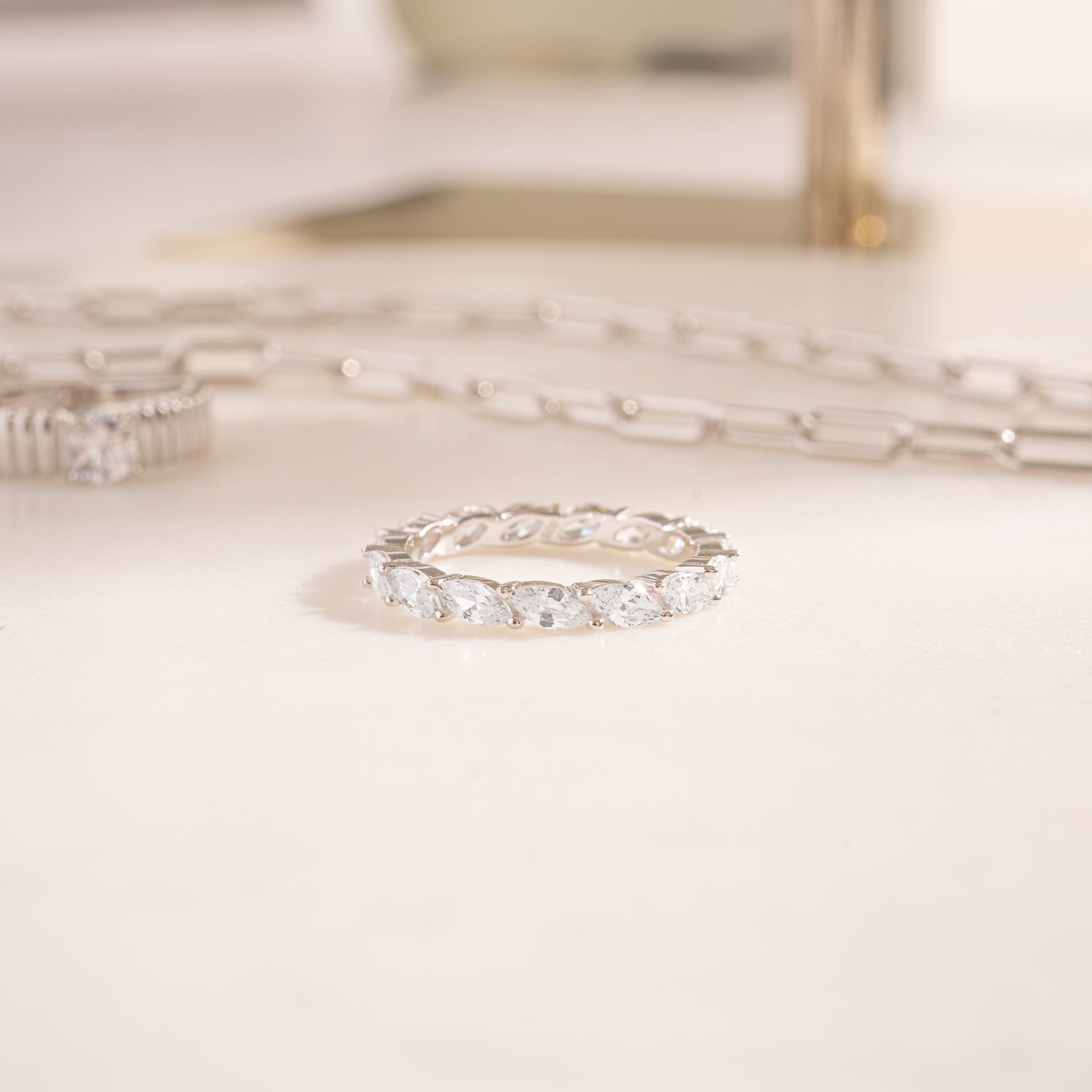 flat lat of a silver ring,  highlighting its marquise stones that are small yet noticeable, creating a refined but slightly sculptural feel. 