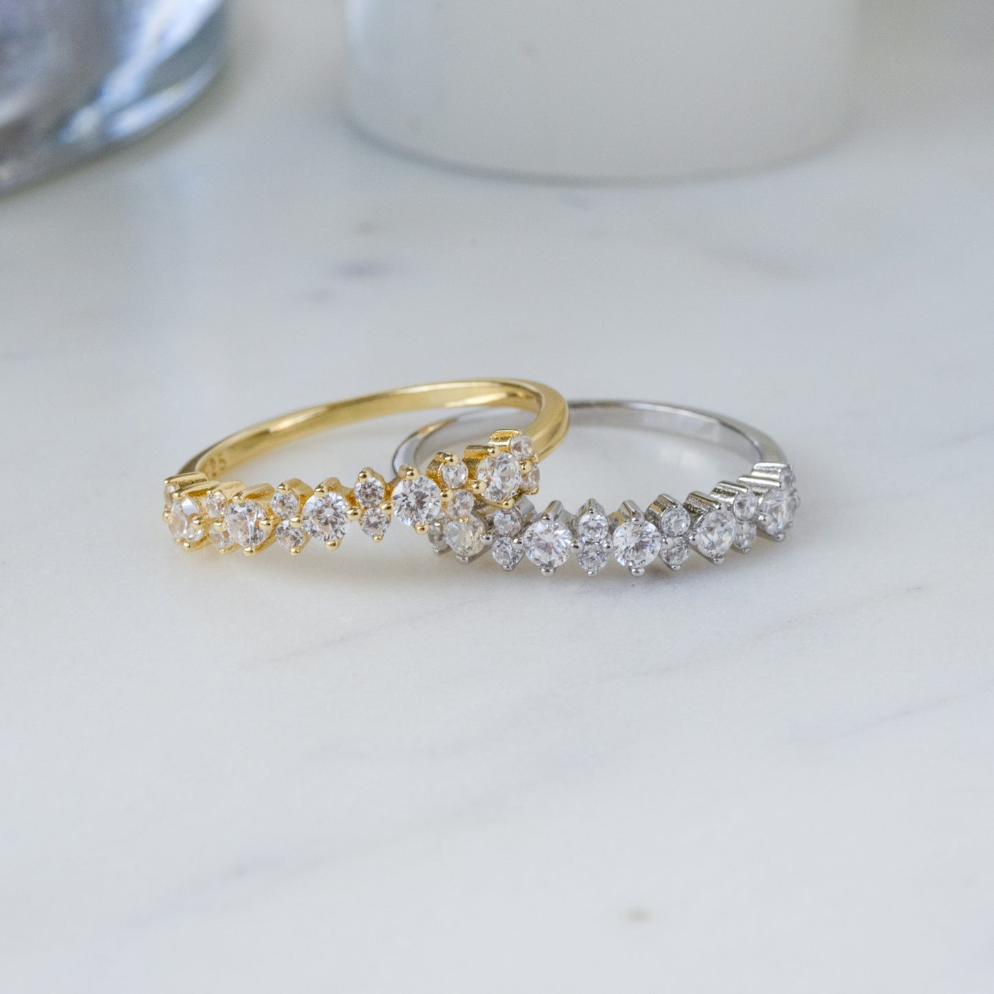 gold diamond ring resting on top of a sterling silver ring with cubic zirconia stones