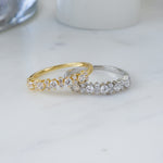 gold diamond ring resting on top of a sterling silver ring with cubic zirconia stones
