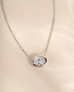 Close-up of the silver oval CZ pendant showing its horizontal bezel setting.