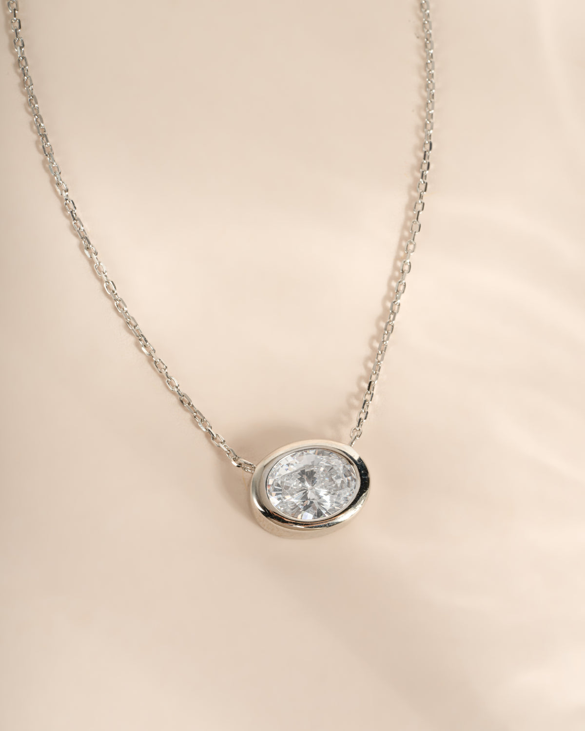Close-up of the silver oval CZ pendant showing its horizontal bezel setting.