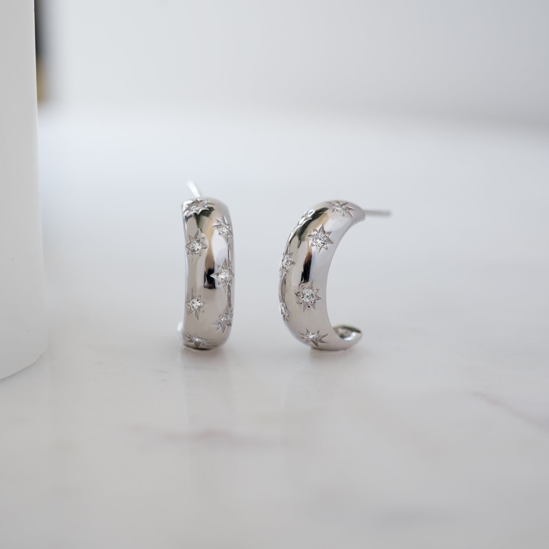 sterling silver hoop earrings with a celestial design. They are small hoops, minimalist and dainty.
