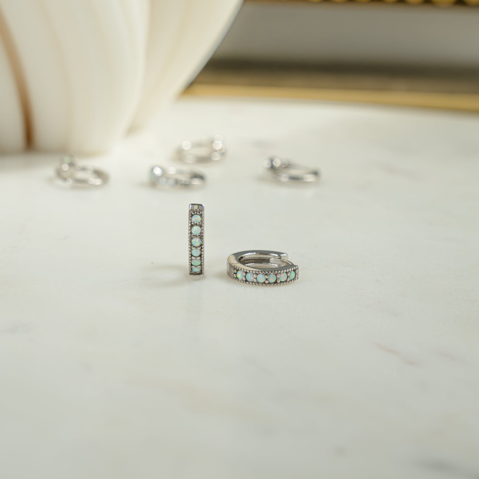 Close up image of sterling silver October birthstone tiny huggie earrings with gorgeous opal stones. 