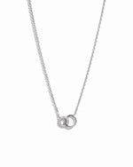 Dainty silver necklace with interlocking infinity circle pendant, with tiny diamond accents on delicate silver chain against a white background